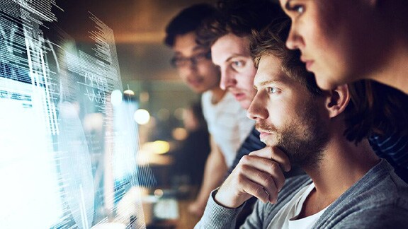 A group of employees looking at the data feeds on the big monitor